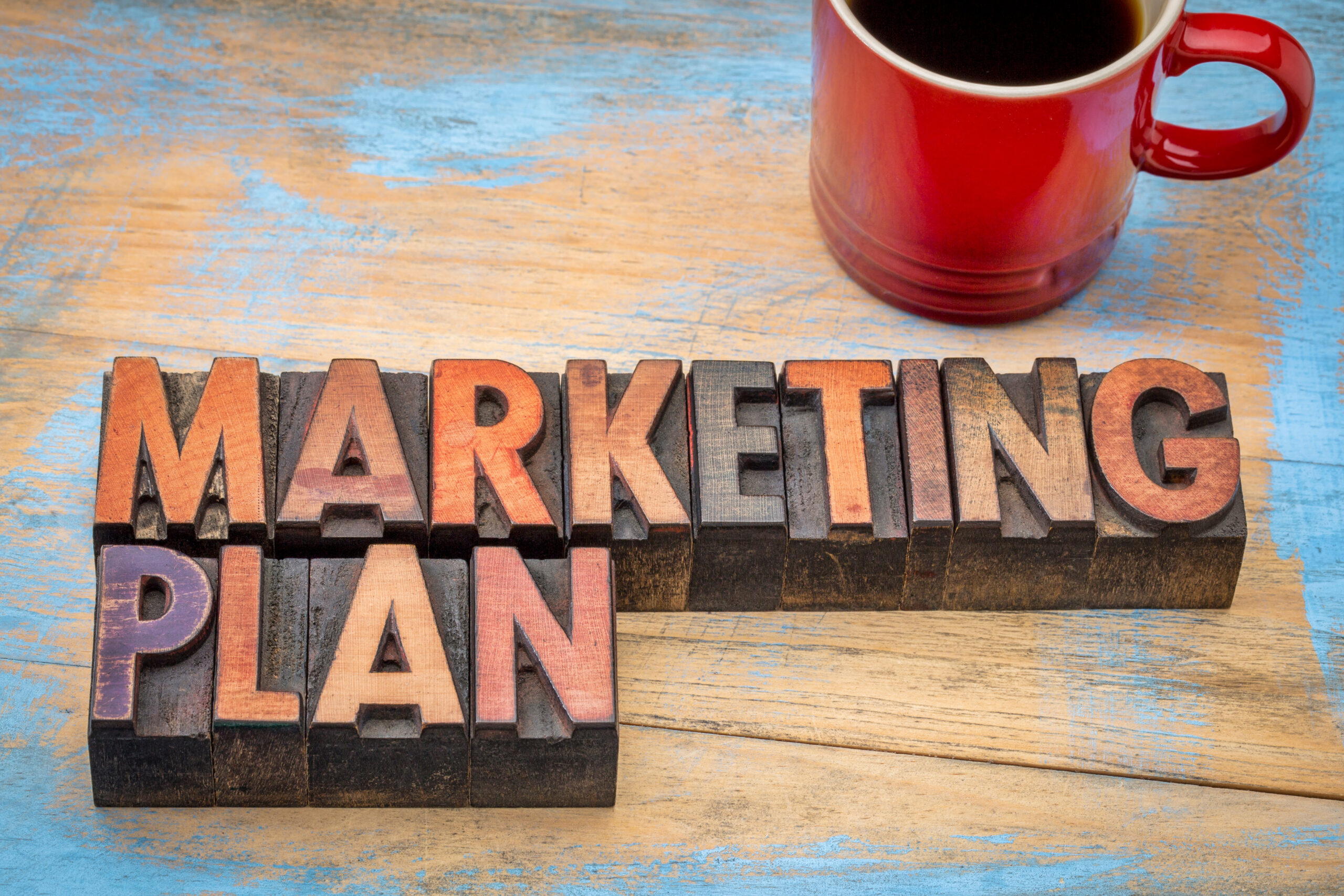 A “Marketing Plan” signboard is placed next to a coffee cup.