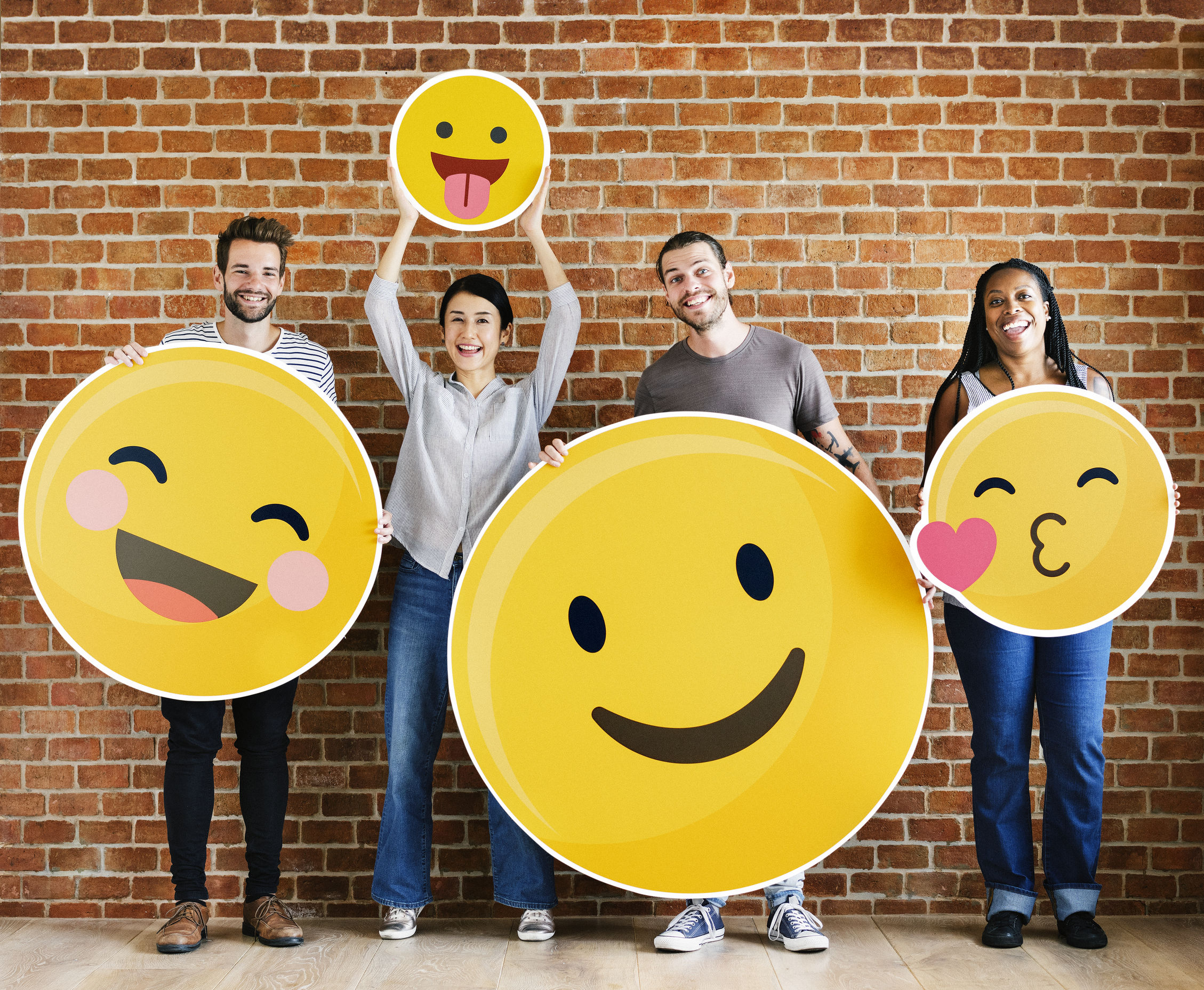 A team of marketers holding cardboard cutouts of various positive emoticons.
