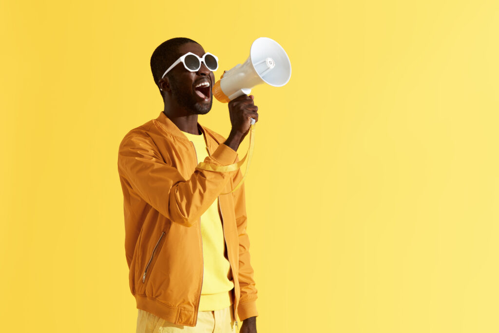 A man dressed in yellow talking into a megaphone.