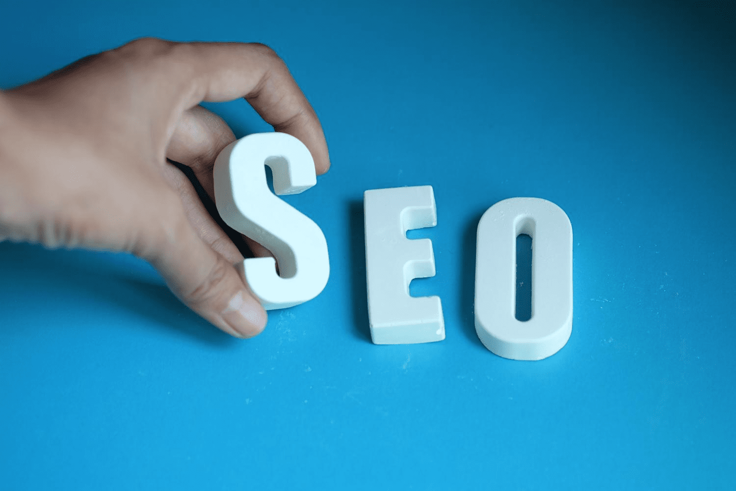 A person holding the word SEO on a blue background.